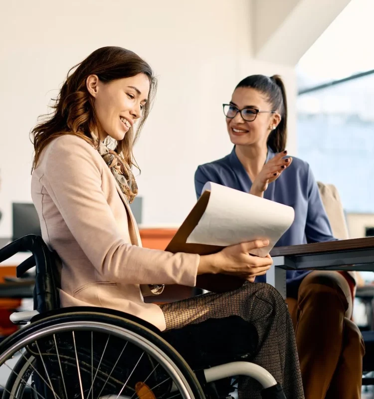 Happy disabled woman in office with support worker