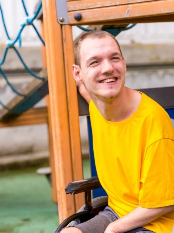 A disabled person in a wheelchair on the swings of a playground
