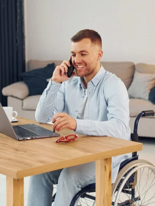 Disabled man in wheelchair at home using laptop