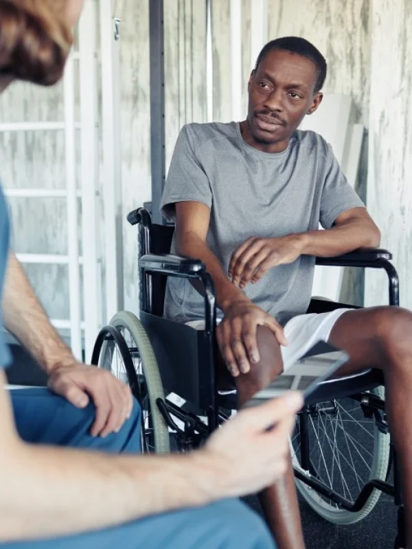 Man in wheelchair talking with nurse in home